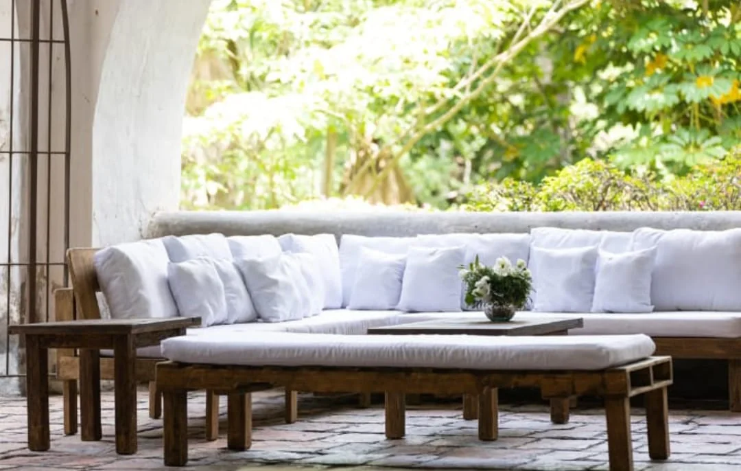 Sala lounge blanca de madera en un patio con vegetación