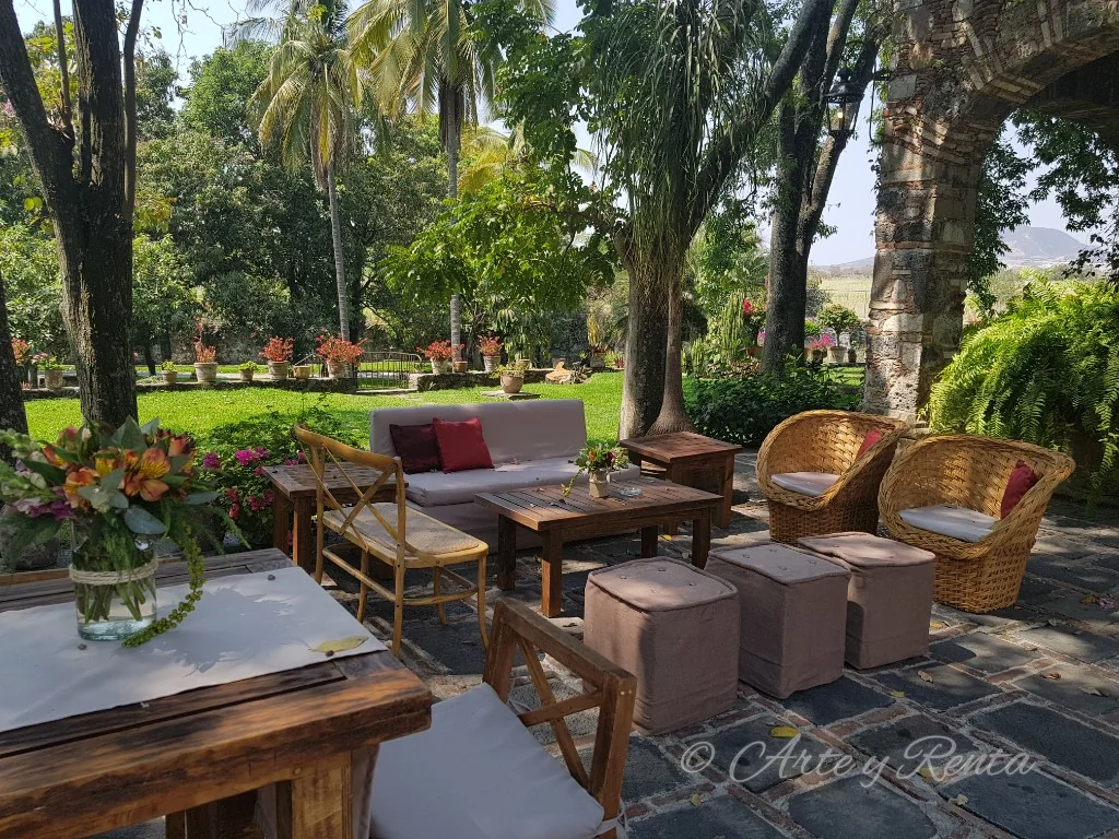 Sala de madera en jardín con vegetación y arquitectura de piedra